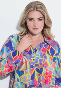 Camicia a maniche lunghe con bottoni, colorata e a motivi, in blu, rosa e giallo. Presenta un colletto, una vestibilità comoda e un design decorativo.