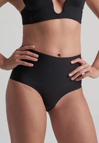 Mutande nere a vita alta in un tessuto liscio ed elastico, con un design senza cuciture e senza parti metalliche visibili, che offrono una copertura totale.