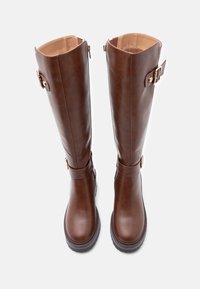 Brown leather knee-high boots with a smooth texture, gold-tone hardware accents, and a side zipper. Chunky sole for added traction.