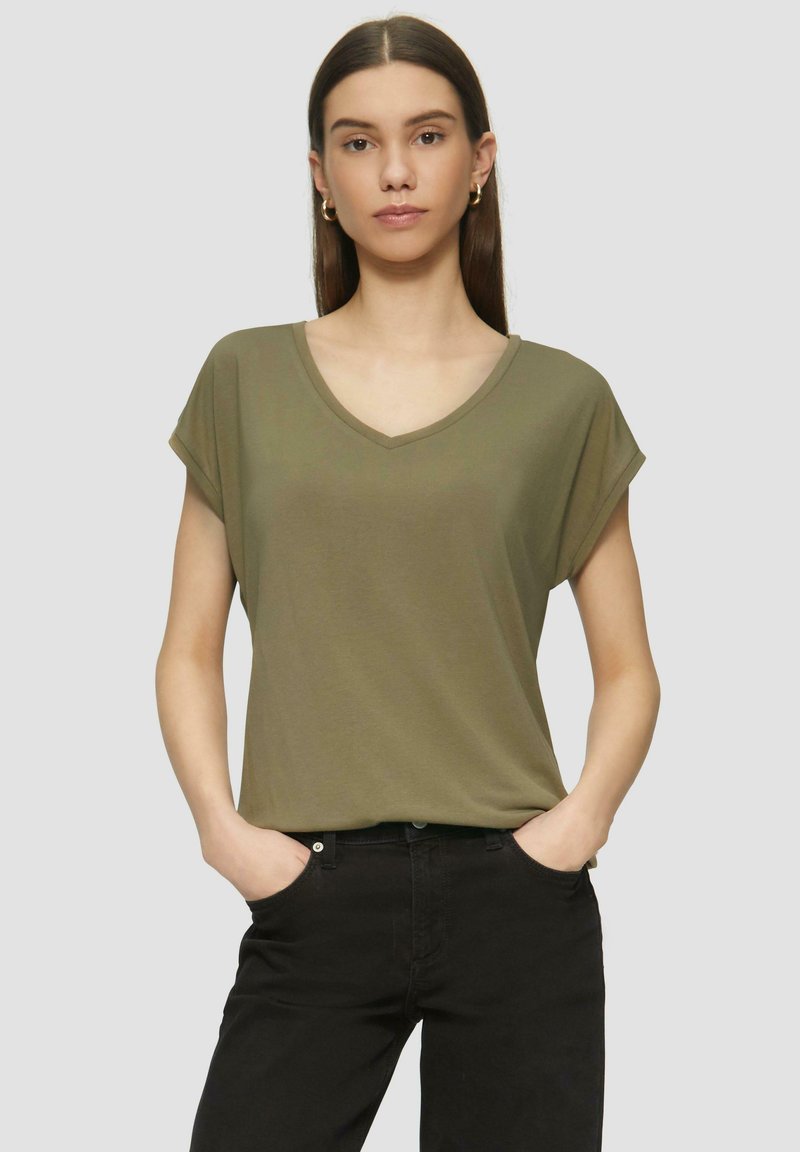 Olivengroene, kortennarmige V-hals T-shirt gemaakt van zacht materiaal, gecombineerd met zwarte broek. Casual pasvorm met opgerolde mouwaccenten.