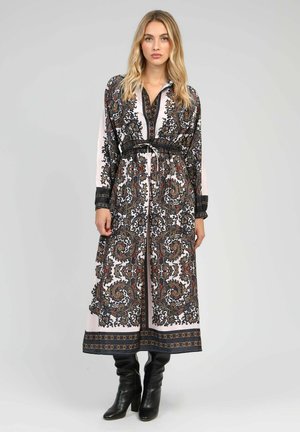 Robe longue à motifs avec des designs paisley complexes en noir, rouge et blanc. Elle a une taille ceinturée flatteuse et un col.