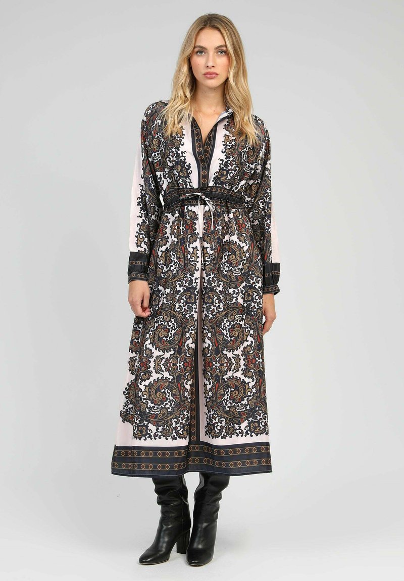 Robe longue à motifs avec des designs paisley complexes en noir, rouge et blanc. Elle a une taille ceinturée flatteuse et un col.