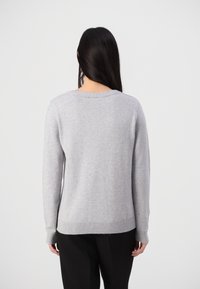 Light gray sweater with a ribbed neckline and cuffs, featuring a relaxed fit and soft texture. Displays a plain design with no visible patterns.