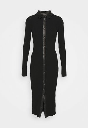 Robe noire côtelée avec un col, des manches longues et une fermeture à boutons sur le devant avec un bord en cuir et une fente centrale.