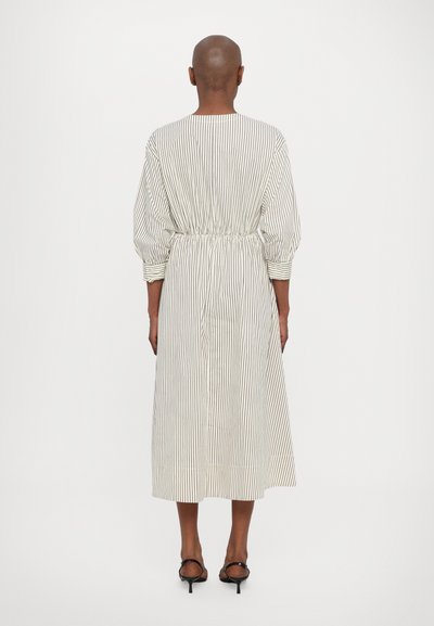 Lätt, randig klänning med insvängd midja, långa ärmar, midi-längd och mjuk textur, kombinerad med svarta sandaletter.