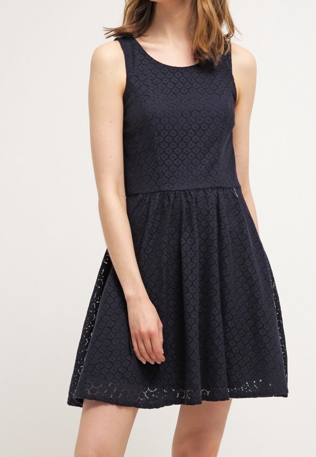 Robe sans manches bleu marine avec un encolure ronde, en tissu dentelle texturée, corsage ajusté et jupe évasée s'étendant jusqu'au mi-cuisse.