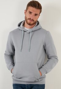 Sudadera gris claro hecha de una suave mezcla de algodón, con un bolsillo frontal, capucha con cordones y puños y dobladillo acanalados.