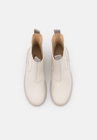 Botines de crema hechos de cuero suave, con paneles laterales elásticos, una pestaña de bucle y una suela de goma de color gris claro.