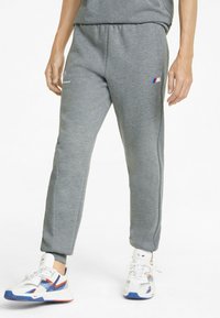 Grey sweatpants feature a tapered design with an elastic waistband, side pockets, and a small logo in red and blue accents.