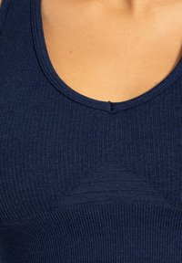 Mörkblå ribbad linne med rundad halsringning, med texturerade detaljer och en figurnära design. Tillverkad av elastisk tyg för komfort.