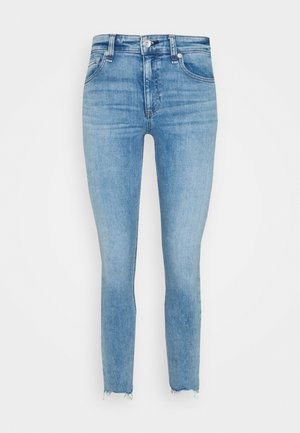 Jean skinny taille haute bleu clair avec poches avant, fermeture par boutons et ourlets effilochés sur fond blanc uni.