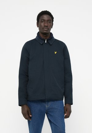 Navy blue jacket with a collar, zip closure, and side pockets. Yellow logo on chest. Made from a smooth, durable fabric.