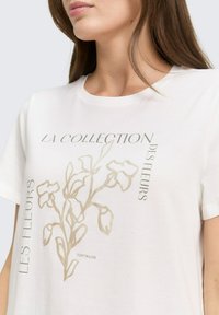 Wit katoenen T-shirt met een bloemenomtrek in licht goud, met de tekst "LA COLLECTION DES FLEURS" en "TOM TAILOR."