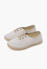 Scarpe in tela beige con punta rotonda, suola in juta e due paia di occhielli per i lacci. Texture liscia con dettagli di cucitura minimi.