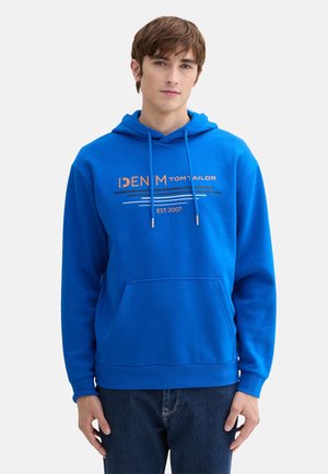 Blauwe hoodie met een voorzak, trekkoorden en logotekst. Het materiaal lijkt zacht met een gladde textuur. Casual pasvorm.