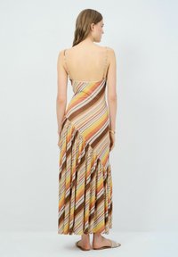 Maxikleid mit diagonalen Streifen in erdigen Tönen von Braun, Gelb und Orange. Verstellbare Spaghettiträger und ein rüschiger Saum.