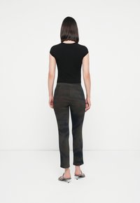 Black fitted t-shirt with short sleeves paired with dark patterned trousers. Trousers feature a textured design and a subtle tie-dye effect.