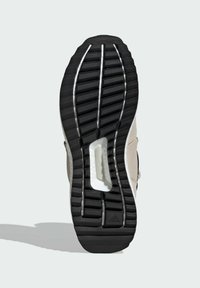 Černá gumová podešev boty s hlubokými vzory, obsahující bílou polstrovanou část a béžový horní materiál. Doplněno stříbrnými detaily.