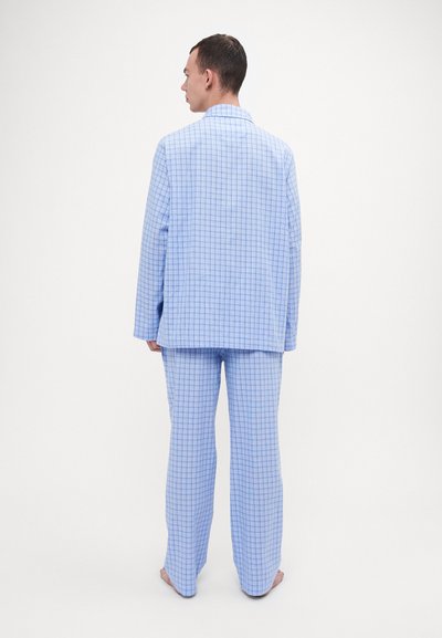 Ensemble de pyjama à carreaux bleus comprenant une chemise col et un pantalon assorti. Fabriqué à partir d'un tissu léger, présentant un motif en grille bleu et blanc.