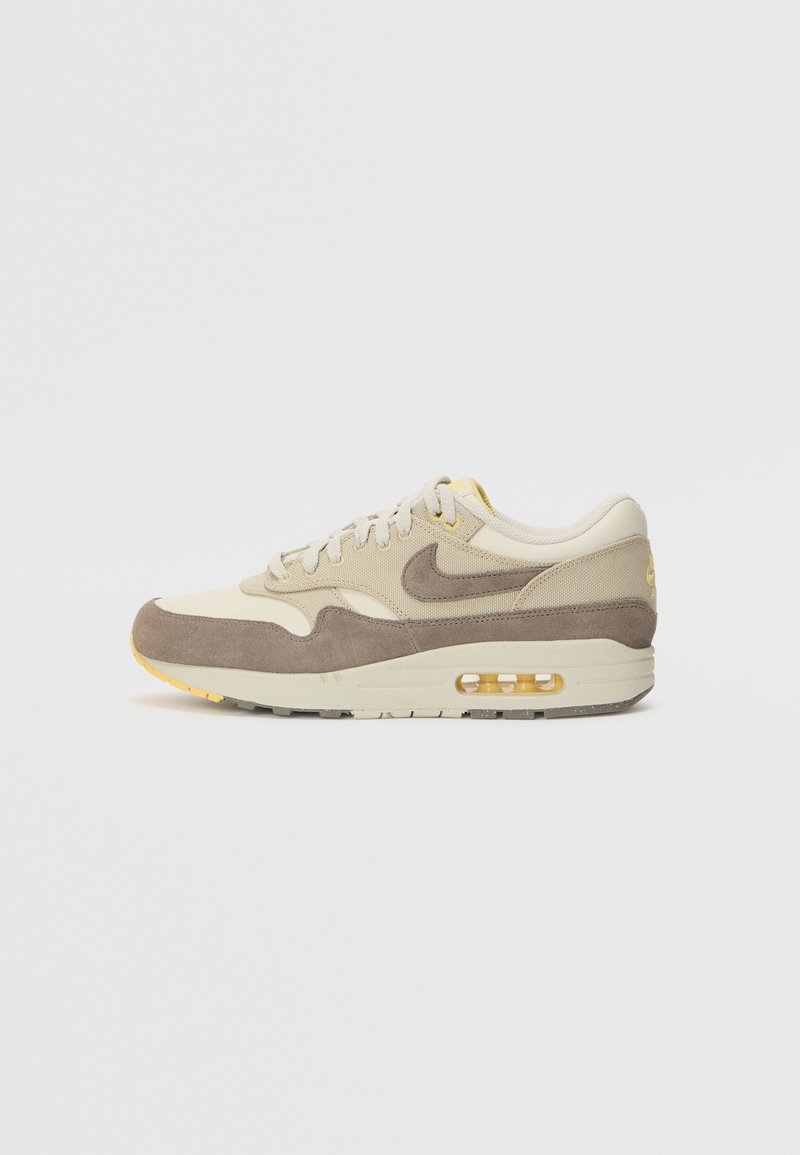 Μπέζ σουέτ και υφασμάτινο αθλητικό παπούτσι, με καφέ λογότυπο σούσι, κίτρινες λεπτομέρειες και διαφανή αέρινη σόλα. Σχεδιασμένο με στρογγυλή μύτη και υφή στην σόλα.