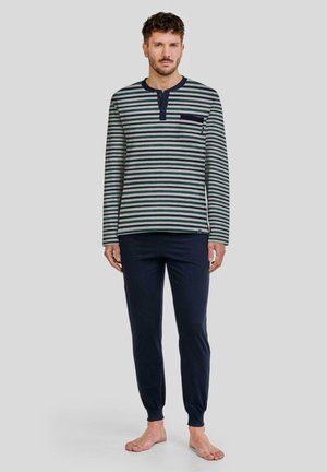 Camisa de manga larga a rayas en verde y crema con un bolsillo en el pecho, combinada con pantalones azul marino sólidos con tobillos ajustados, confeccionados en tejido suave.