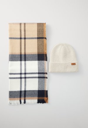 Plaid scarf in beige, white, and navy, with fringe edges; ribbed cream knit beanie with a small leather patch.