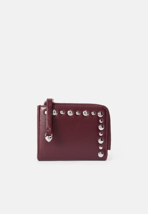 Portefeuille en cuir bordeaux avec fermeture éclair, orné de rivets en argent sur un côté et d'une petite sangle avec une quincaillerie en forme de cœur.