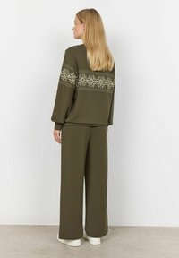 Sada volnočasového oblečení v olivově zelené barvě, která obsahuje sweatshirt s bílými vzory sněhových vloček a kalhoty s širokými nohavicemi. Hladká textura, uvolněný střih.