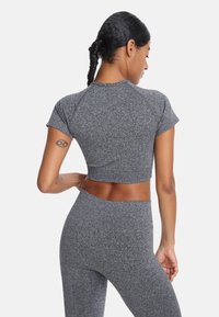 Top corto atlético gris y leggings de cintura alta, confeccionados con un tejido texturizado con un patrón jaspeado, que presentan mangas cortas y un diseño ajustado.