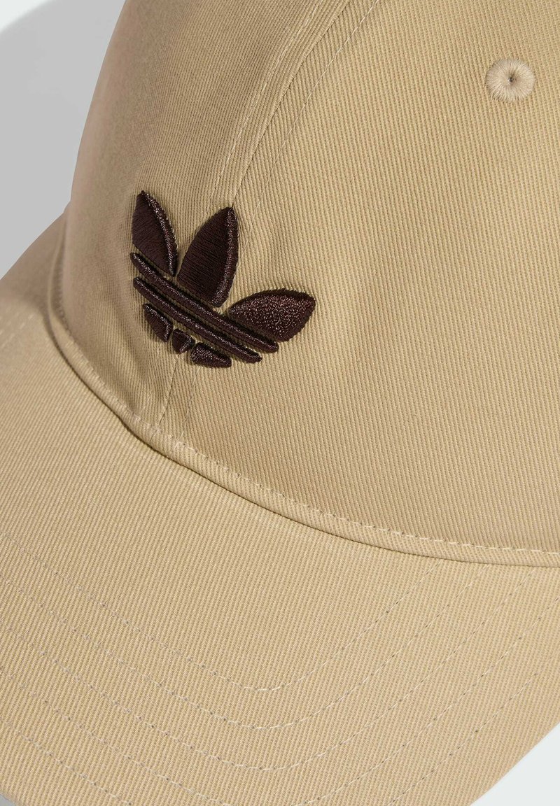 Beige Baseballkappe aus strukturiertem Stoff mit einem dunkelbraunen, bestickten Logo mit Blattmuster und horizontalen Streifen.