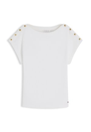 Hvid kortærmet top med guldknapdetaljer langs skuldrene og en lille logo nær kanten.