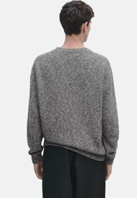 Maglione grigio a maglia con scollatura rotonda, polsini a costine e una vestibilità comoda. Materiale morbido e testurizzato, con un sottile motivo melangiato.