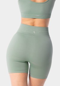 Hoge taille groene geribbelde shorts hebben een zachte textuur en een naadloos ontwerp, waardoor een getailleerde silhouette wordt benadrukt.