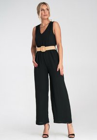 Czarny kombinezon bez rękawów z dekoltem V i szerokimi nogawkami, z plecionym beżowym paskiem z kwadratową klamrą dla dodatkowych detali.