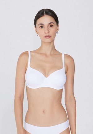 White, wireless bra with smooth, molded cups and thin adjustable straps. Features a seamless design and soft, stretchy fabric for comfort.