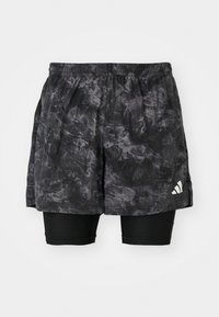 Shorts de sport noirs avec un motif marbré et des shorts de compression intérieurs. Ils présentent une taille élastique et un petit logo blanc sur le côté.
