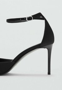 Czarny szpilka z gładką, matową powierzchnią, wyposażona w cienki pasek wokół kostki i spiczasty przód. Podeszwa ma błyszczące wykończenie.