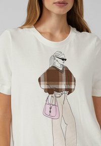 White t-shirt featuring a graphic of a figure in a brown plaid sweater, holding a pink bag, with sunglasses and a ponytail.