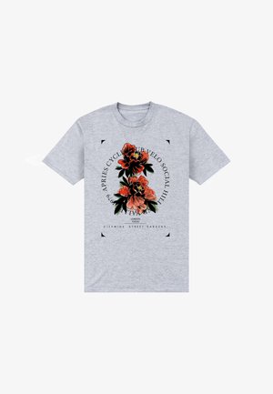 T-shirt in cotone grigio con un design grafico floreale in arancione e verde, con elementi testuali e un design a forma rotonda sulla parte anteriore.