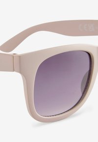 Lunettes de soleil en plastique beige avec des montures angulaires et des verres dégradés violets. Présente un design épuré avec une charnière flexible pour plus de confort.