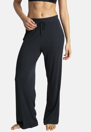 Pantalons de lounge noirs à côtes avec une taille élastique et un cordon de serrage. Ils ont une coupe décontractée et se resserrent légèrement vers la cheville.