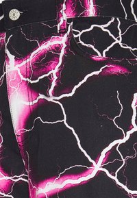 Jeans pretos com um padrão de raio em branco e rosa. Apresenta um bolso frontal, botão de metal e costura em contraste. Textura de denim durável.