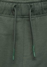 Dark green fabric joggers with a drawstring waistband. Features include textured fabric, reinforced seams, and rubberized tips on the drawstrings.