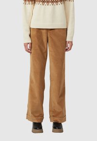 Bruine corduroy wijdlopende broek met een zachte textuur, voorzien van een hoge taille en opgerolde manchetten, gecombineerd met een crèmekleurige trui.
