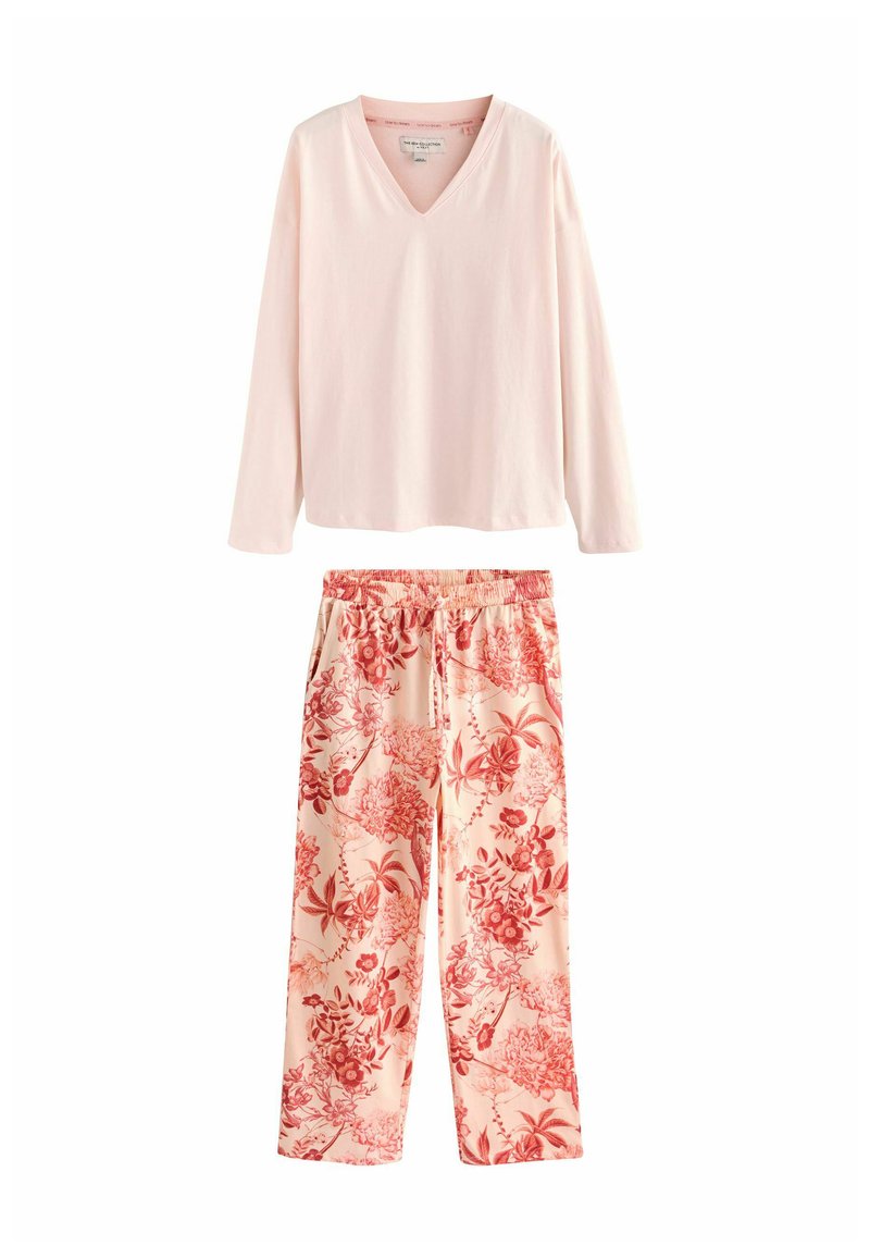 Bluză roz deschis cu mânecă lungă și guler în V, combinată cu pantaloni florali cu modele roșii și roz, talie elastică și croială lejeră.