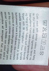 Označenie starostlivosti s ikonami prania a viacjazyčnými pokynmi pre studené pranie, bez bielenia, sušenie v sušičke na nízkej teplote, žehlenie na nízkej teplote a zákaz čistenia chemickým spôsobom.