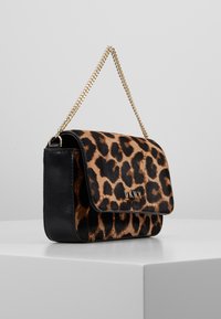 Kabelka s leopardím potiskem a černými koženými akcenty, s zlatým řetízkem a klopovým zapínáním. S logem DKNY na přední straně.