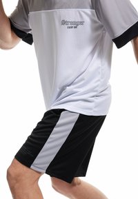 Vit och svart atletisk skjorta med korta ärmar och mesh-textur, med texten "Stronger EVERY DAY". Svarta shorts med grå detaljer.