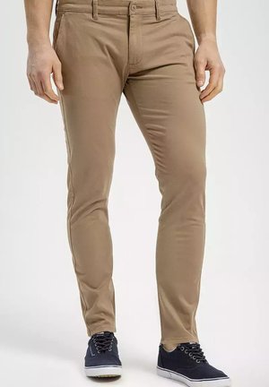 Khaki chinos o slim fit, wykonane z tkaniny mieszanej bawełnianej. Posiadają kieszenie z przodu, szlufki na pasek oraz podwinięte mankiety. W zestawie z ciemnymi sneakersami.