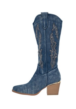 Botas de vaquero de denim con puntera afilada, adornadas con patrones de tachuelas plateadas y un tacón apilado, con un acento dorado en la base del tacón.